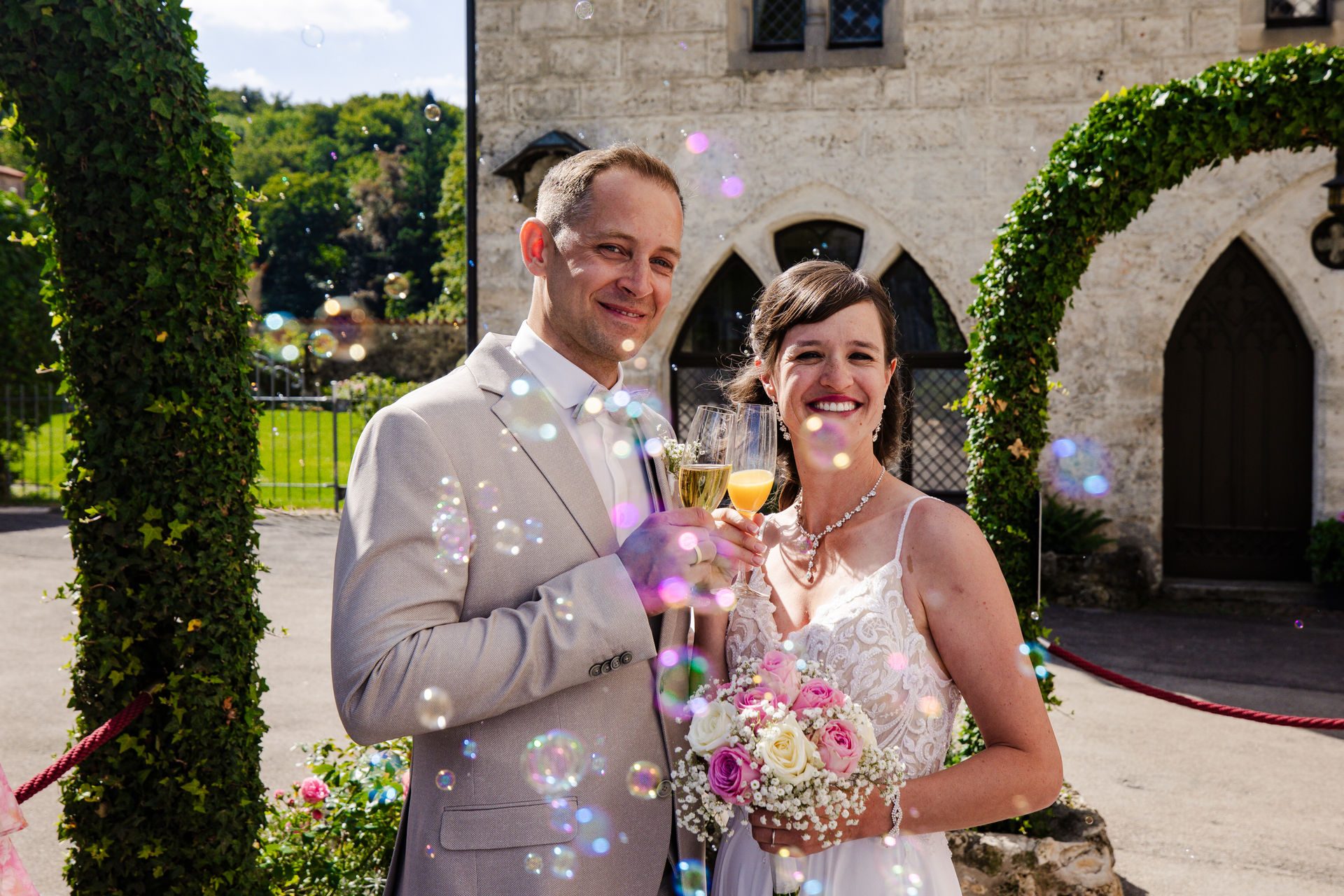 Brautpaar mit Sektgläsern im Schlosshof von Schloss Lichtenstein