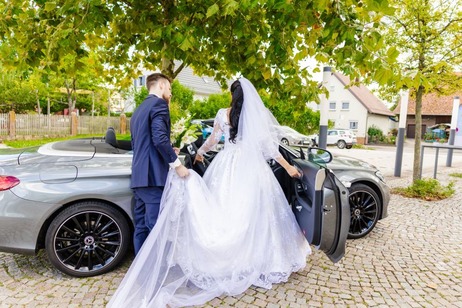 Brautpaar mit dem Hochzeitsauto zur Feier