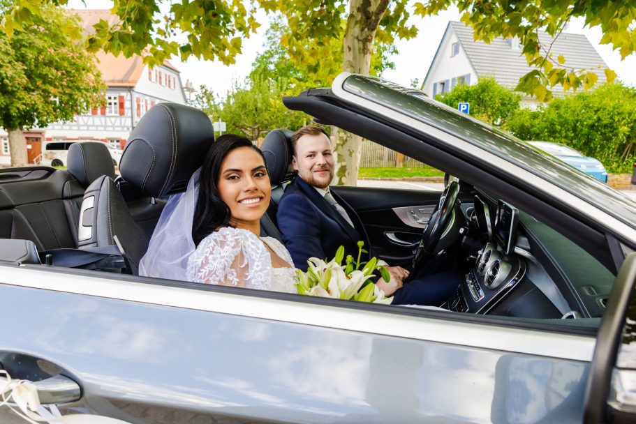 Brautpaar mit dem Hochzeitsauto zur Feier