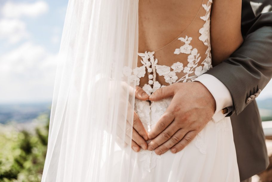 Detailaufnahme von Brautkleid und Händen des Brautpaares