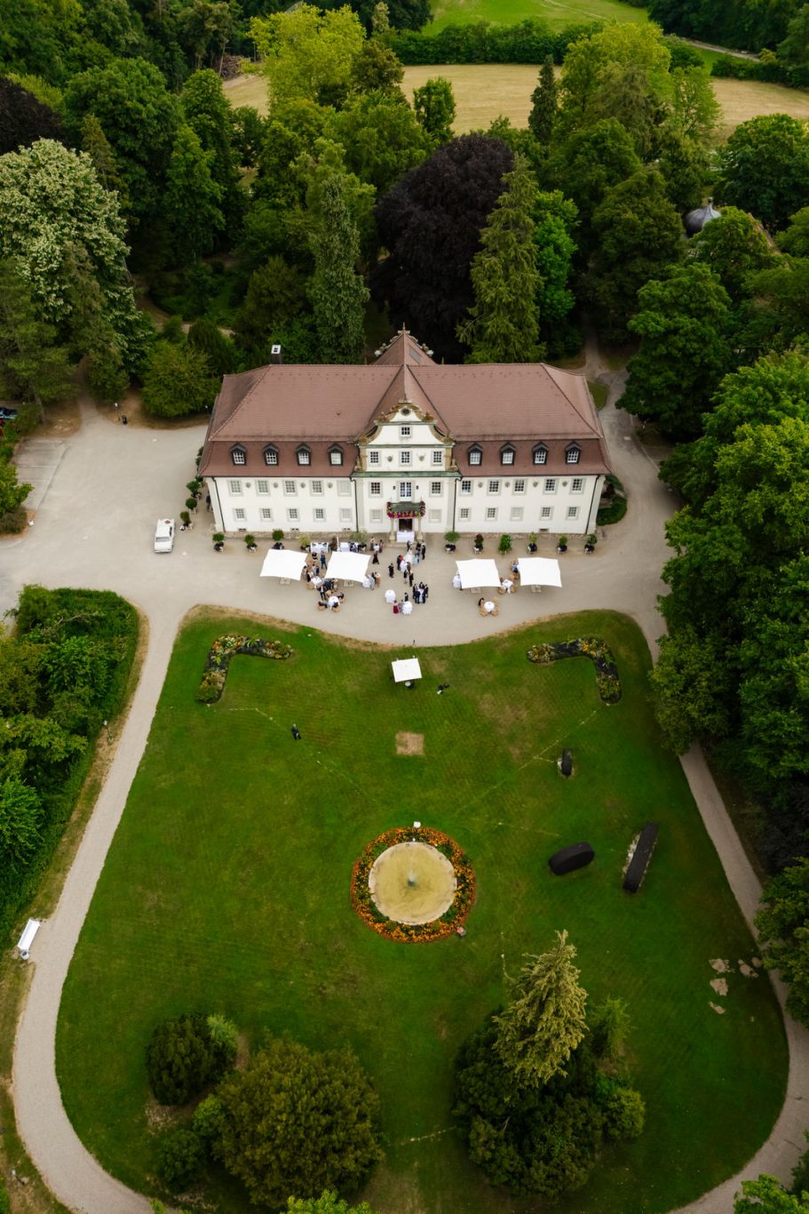 Schlosshotels Friedrichsruhe mit Garten und Bäumen, umgeben von Wiese und Wegen.