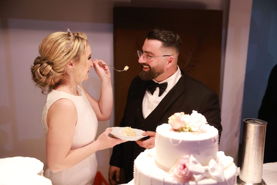 Brautpaar beim Anschneiden der Hochzeitstorte mit Gästen