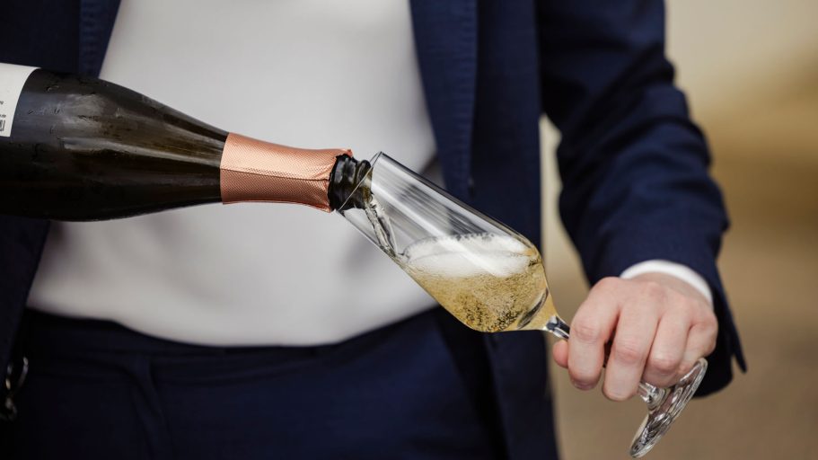 Sektempfang. Sekt wird in eine Glasflöte eingeschenkt.
