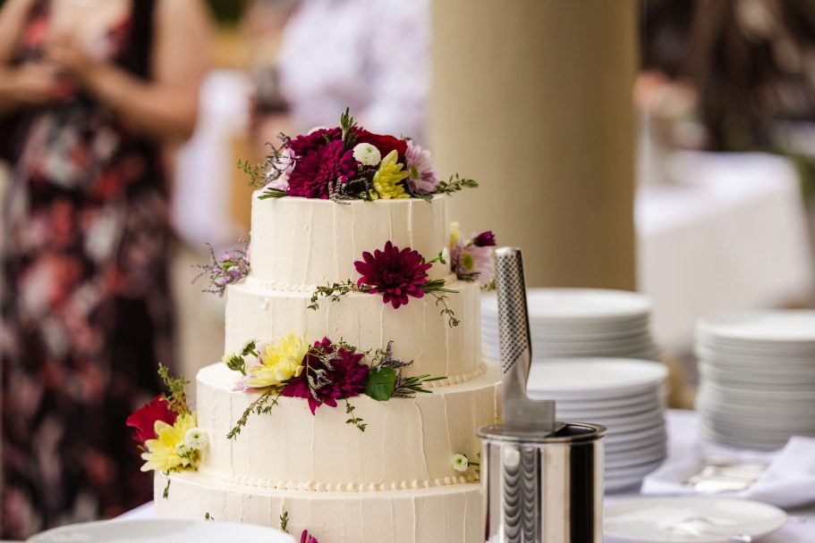 Drei-stöckige Hochzeitstorte geschmückt mit bunten Blumen.