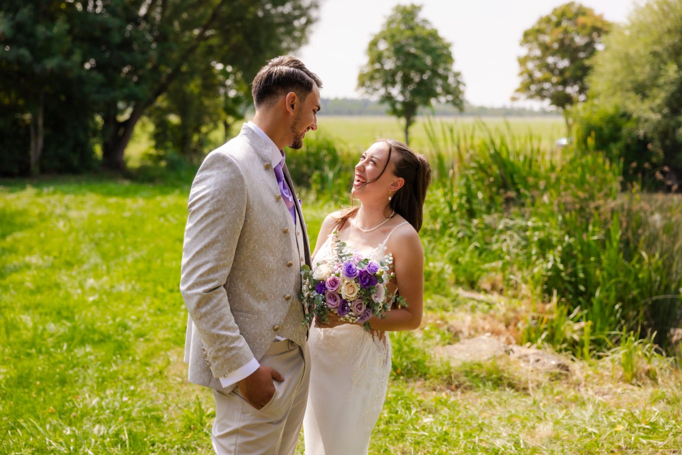 Braut und Bräutigam beim First Look auf einer Wiese