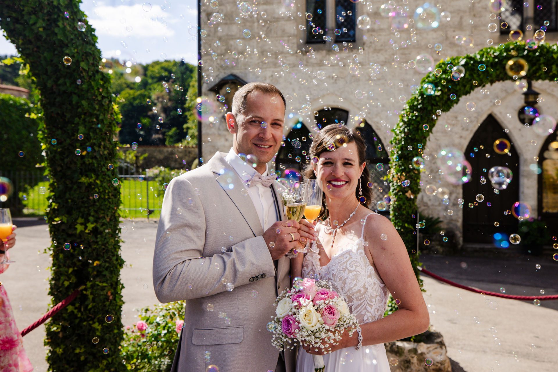 Brautpaar mit Sektgläsern im Schlosshof von Schloss Lichtenstein