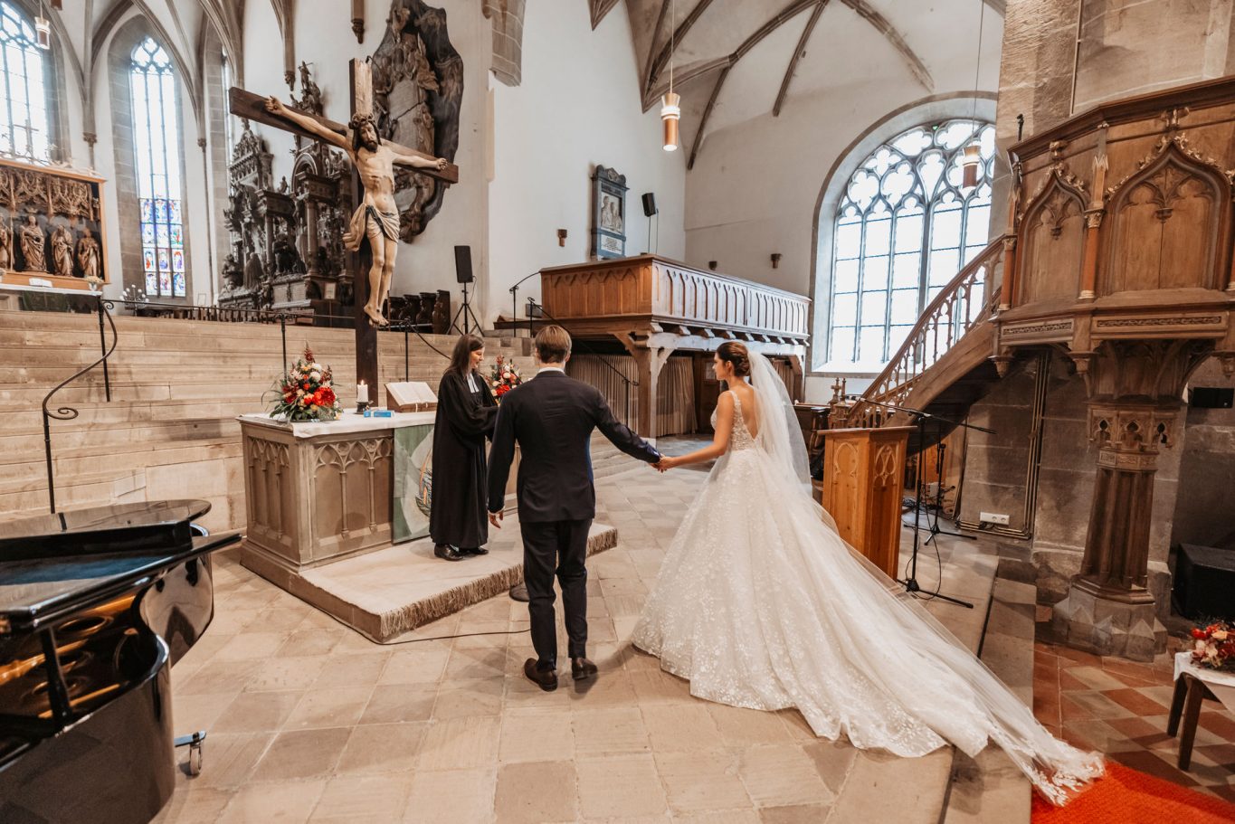 Brautpaar steht während der Zeremonie in Stiftskirche Öhringen  vor dem Altar.