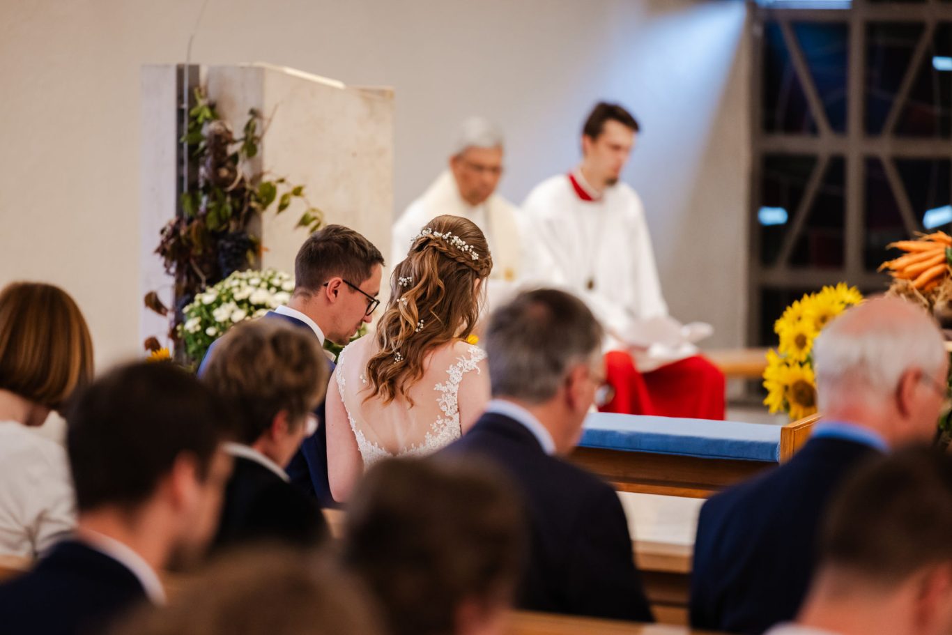 Brautpaar und Hochzeitsgäste während der kirchlichen Trauung